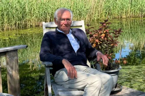 Meneer zittend in een stoel aan het water