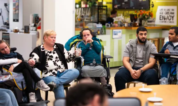 Cliënten en begeleiders drinken samen koffie