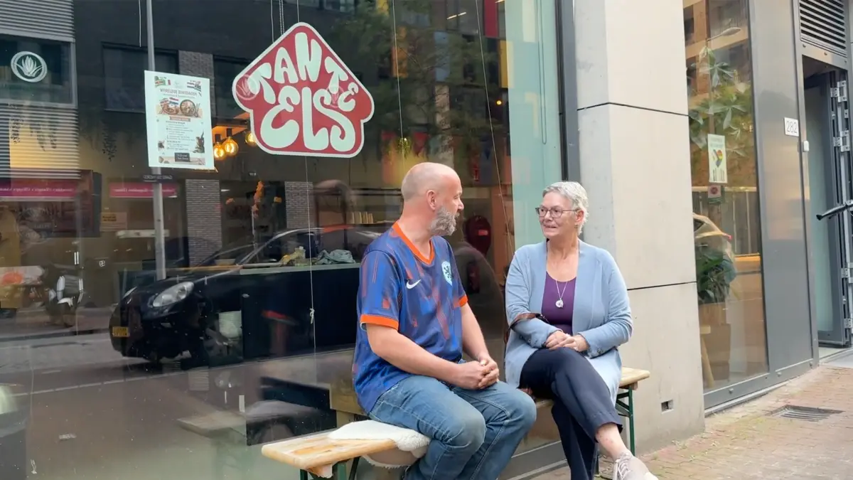 Een man en vrouw praten buiten op een bankje